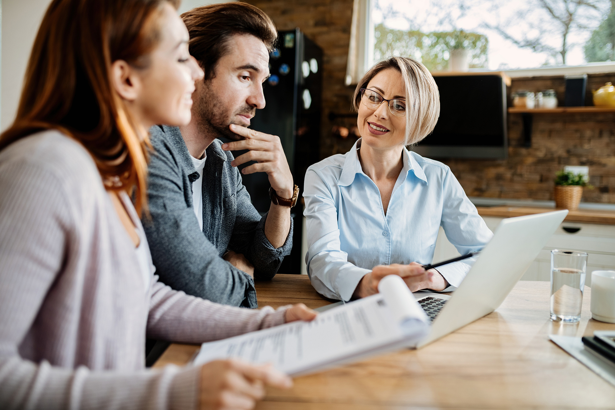 smiling-financial-advisor-using-laptop-while-having-meeting-with-young-couple-1